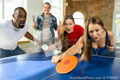 Image of Young people playing table tennis in workplace, having fun