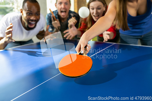 Image of Young people playing table tennis in workplace, having fun