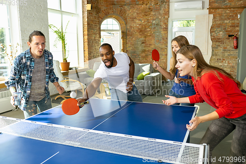 Image of Young people playing table tennis in workplace, having fun