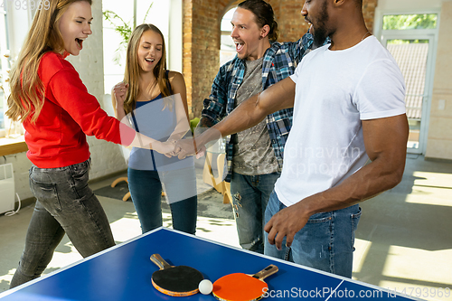 Image of Young people playing table tennis in workplace, having fun