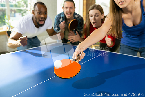 Image of Young people playing table tennis in workplace, having fun