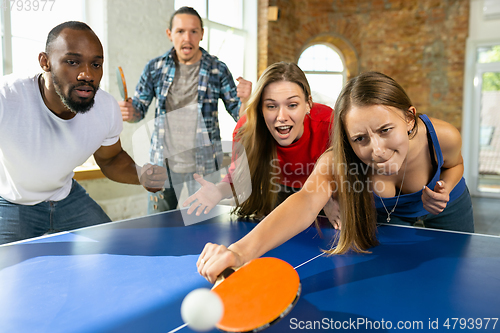 Image of Young people playing table tennis in workplace, having fun