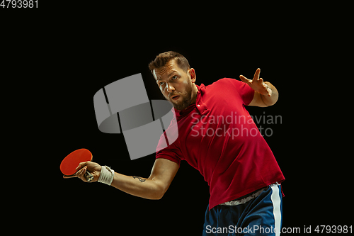 Image of Young man playing table tennis on black studio background