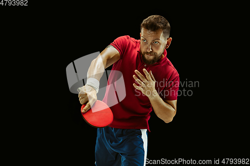 Image of Young man playing table tennis on black studio background