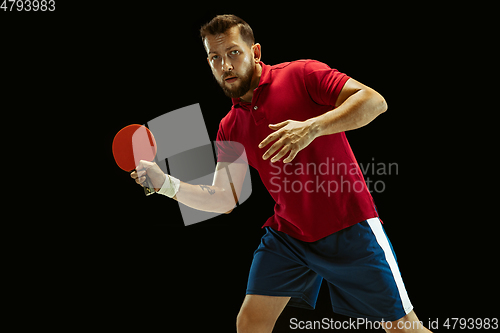 Image of Young man playing table tennis on black studio background