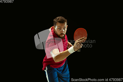 Image of Young man playing table tennis on black studio background