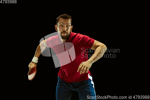 Image of Young man playing table tennis on black studio background