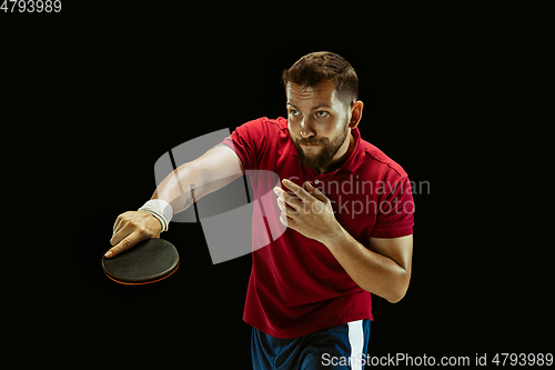 Image of Young man playing table tennis on black studio background