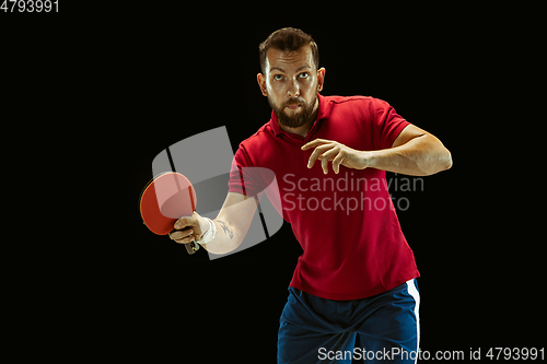 Image of Young man playing table tennis on black studio background