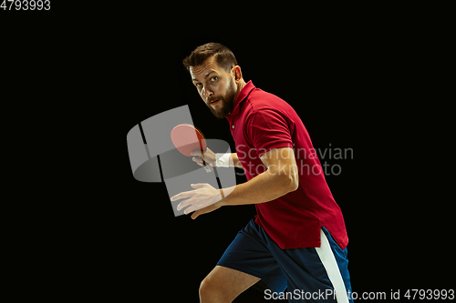 Image of Young man playing table tennis on black studio background