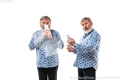 Image of Senior man arguing with himself on white studio background.