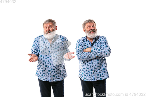 Image of Senior man arguing with himself on white studio background.