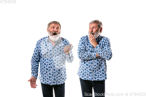 Image of Senior man arguing with himself on white studio background.