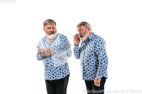 Image of Senior man arguing with himself on white studio background.