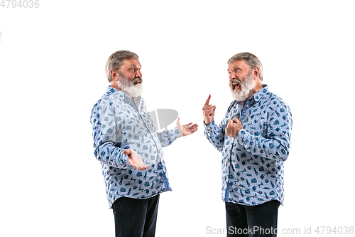 Image of Senior man arguing with himself on white studio background.