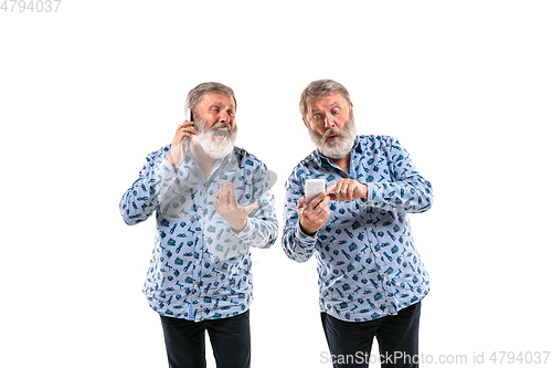 Image of Senior man arguing with himself on white studio background.