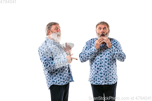 Image of Senior man arguing with himself on white studio background.