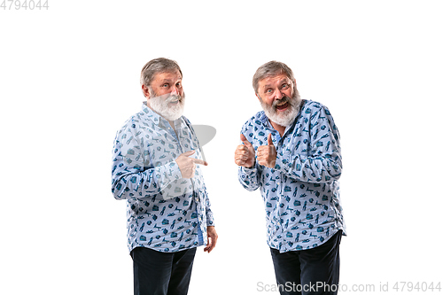 Image of Senior man arguing with himself on white studio background.