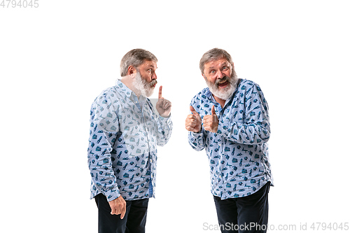 Image of Senior man arguing with himself on white studio background.