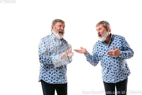 Image of Senior man arguing with himself on white studio background.