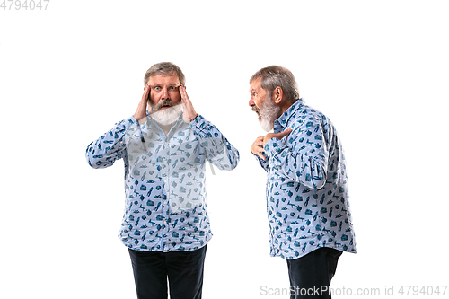 Image of Senior man arguing with himself on white studio background.