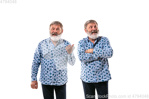 Image of Senior man arguing with himself on white studio background.