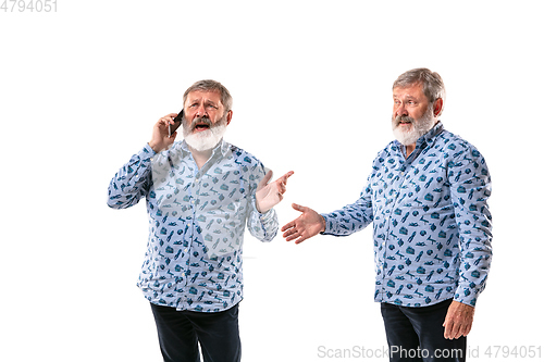 Image of Senior man arguing with himself on white studio background.