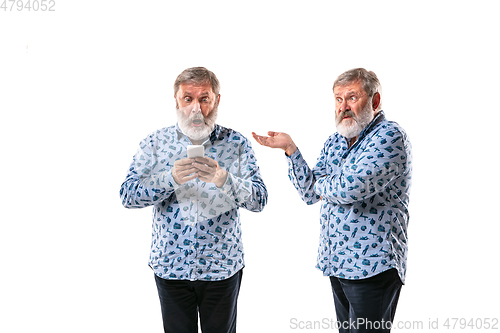 Image of Senior man arguing with himself on white studio background.