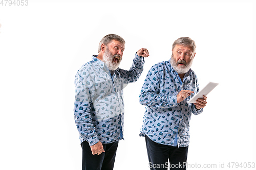 Image of Senior man arguing with himself on white studio background.