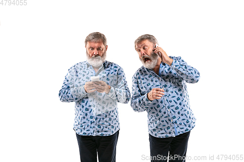 Image of Senior man arguing with himself on white studio background.