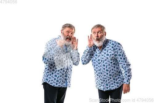 Image of Senior man arguing with himself on white studio background.