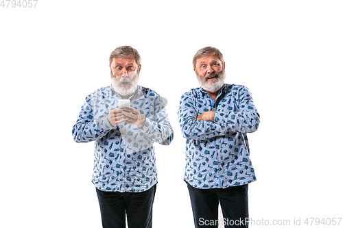 Image of Senior man arguing with himself on white studio background.