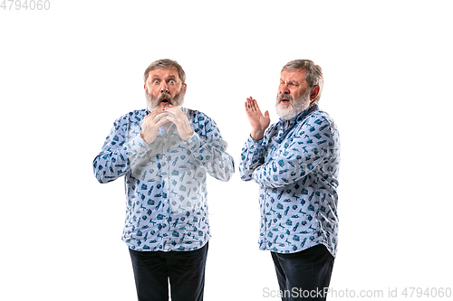 Image of Senior man arguing with himself on white studio background.