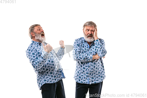 Image of Senior man arguing with himself on white studio background.