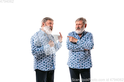 Image of Senior man arguing with himself on white studio background.