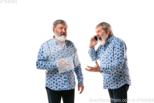 Image of Senior man arguing with himself on white studio background.