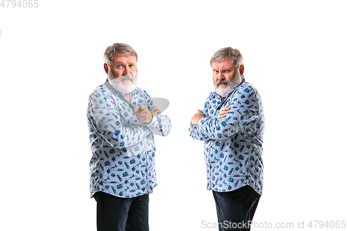 Image of Senior man arguing with himself on white studio background.