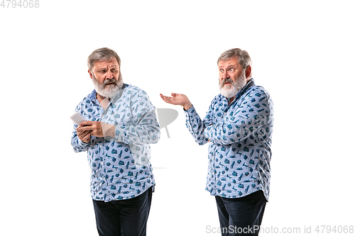 Image of Senior man arguing with himself on white studio background.