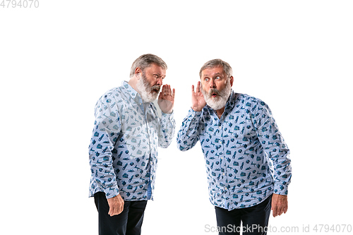 Image of Senior man arguing with himself on white studio background.