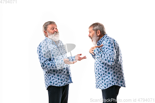 Image of Senior man arguing with himself on white studio background.