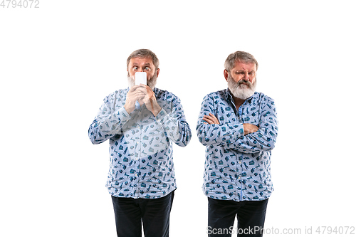 Image of Senior man arguing with himself on white studio background.