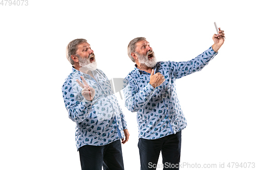 Image of Senior man arguing with himself on white studio background.