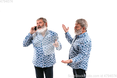 Image of Senior man arguing with himself on white studio background.