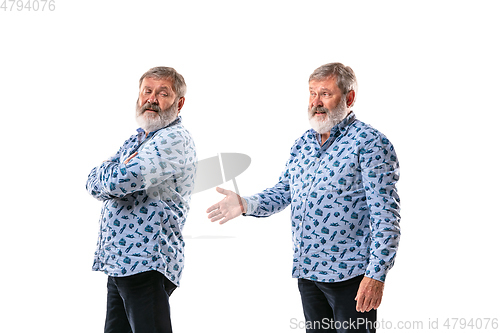 Image of Senior man arguing with himself on white studio background.