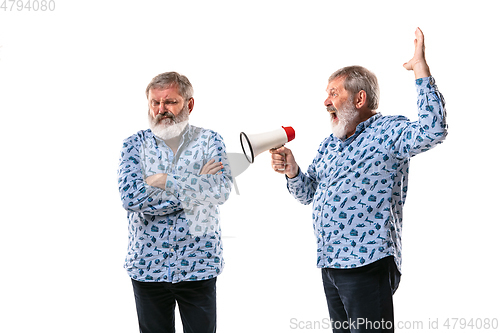 Image of Senior man arguing with himself on white studio background.