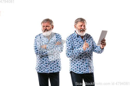 Image of Senior man arguing with himself on white studio background.