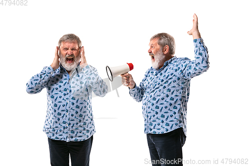 Image of Senior man arguing with himself on white studio background.