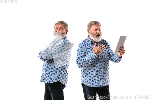 Image of Senior man arguing with himself on white studio background.