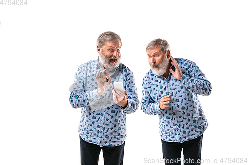 Image of Senior man arguing with himself on white studio background.