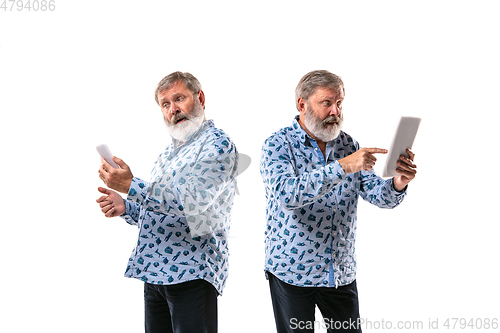 Image of Senior man arguing with himself on white studio background.